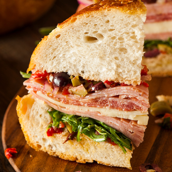 Artisan sandwich with layers of meats, greens, and vibrant ingredients, perfect for a satisfying meal.