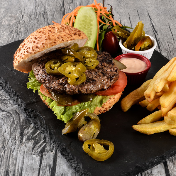 Delicious hamburger with French fries and fresh vegetables on a sleek slate plate.