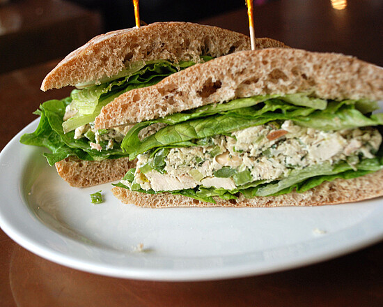 Hearty chicken salad sandwich with fresh lettuce on whole grain bread, artfully presented on a plate.