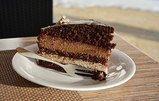 Indulgent chocolate cake slice with glossy ganache and rich mousse, perfect for dessert lovers.