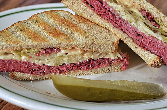 Savory Reuben sandwich with corned beef, sauerkraut, and pickle on a toasted whole grain bread.