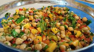 Colorful chickpea salad with fresh vegetables and herbs in a vibrant glass bowl.