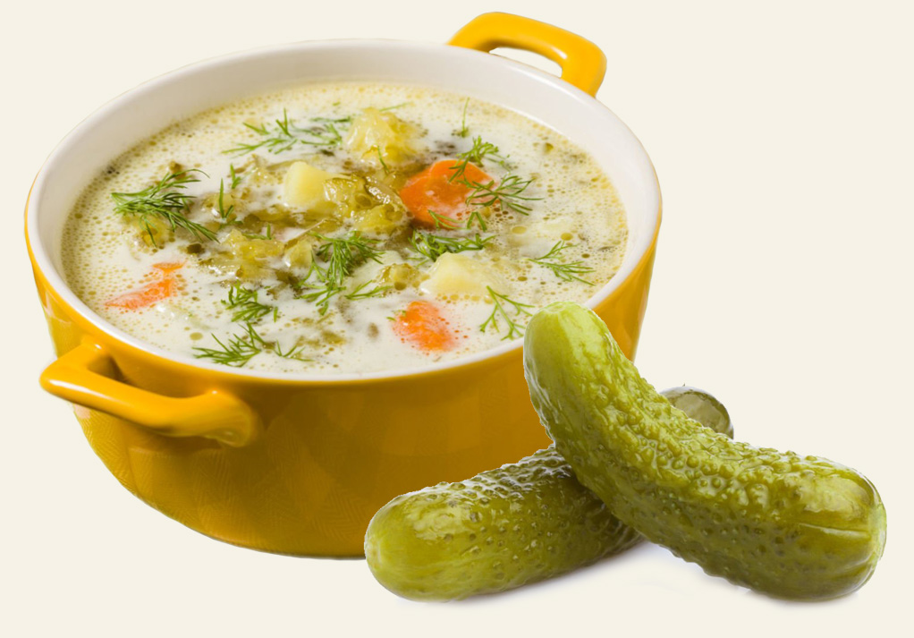 Vibrant creamy vegetable soup in a yellow bowl, garnished with fresh herbs and pickles.