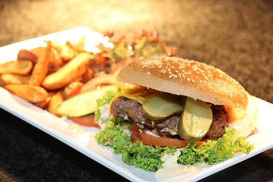 Delicious burger with toasted bun, fresh toppings, and crispy fries on a stylish plate.