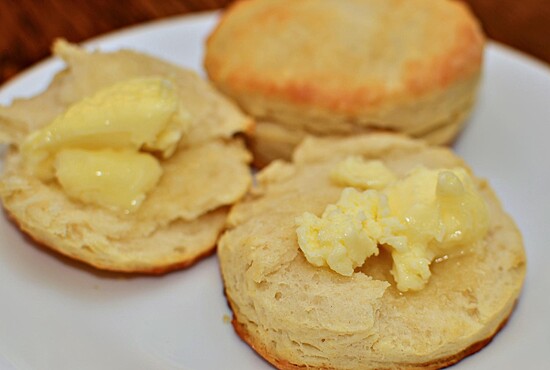 Golden-brown homemade biscuits topped with melting butter, perfect for cozy breakfasts and family gatherings.