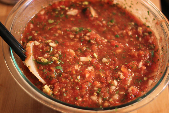 Fresh chunky salsa with tomatoes, onions, cilantro, and peppers, served with a black spoon.