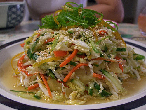 Colorful fresh vegetable salad with cabbage, cucumbers, carrots, and sesame seeds drizzled in dressing.