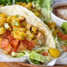 Fresh taco filled with tomatoes, lettuce, and mango, served with creamy sauce.