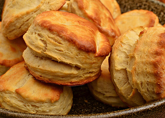 Delicious freshly baked biscuits in a rustic bowl, showcasing golden-brown crusts and flaky layers.