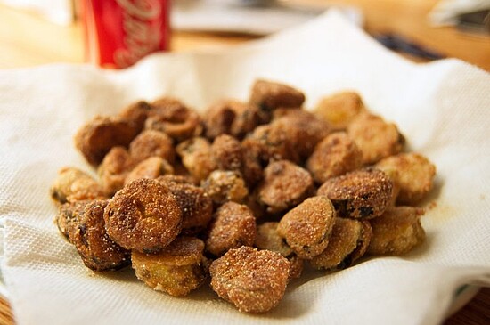 Crispy fried dill pickles served on a paper towel with a refreshing Coca-Cola.