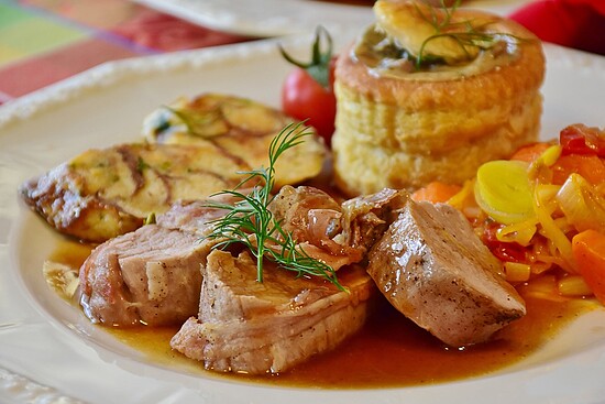 Elegant gourmet plate featuring tender meat, vegetable frittata, colorful sautéed veggies, and flaky pastry.