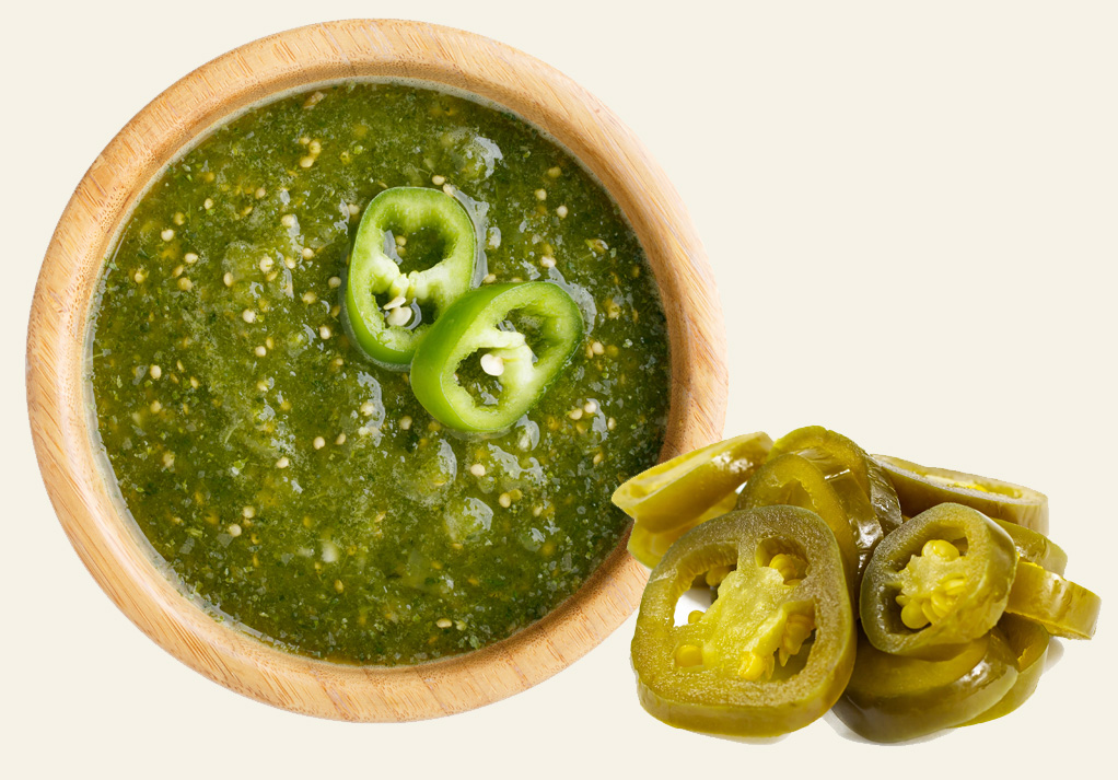 Vibrant green sauce with jalapeños in a wooden bowl, perfect for tacos and dipping.