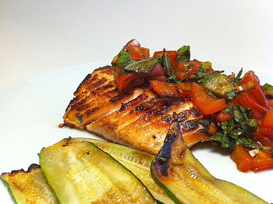 Grilled salmon topped with fresh salsa, served with charred zucchini for a healthy meal.