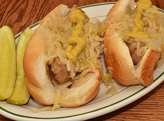 Succulent hot dogs topped with sauerkraut and dill pickles on a rustic wooden table.