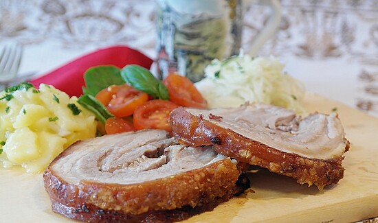 Hearty pork with creamy mashed potatoes, cherry tomatoes, and cabbage on a cozy table setting.