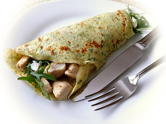 Herb chicken wrap with creamy cheese, arugula, and golden-brown exterior on a white plate.