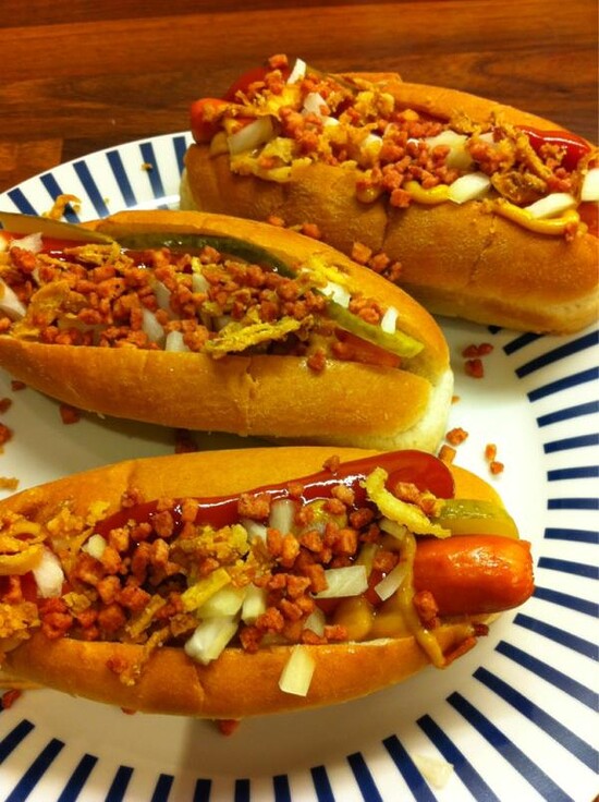 Mouth-watering hot dogs with bacon, onions, ketchup, and pickles on a striped plate.