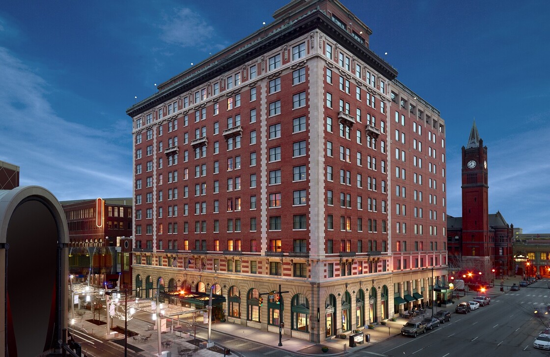 Elegant hotel at dusk, featuring red brick architecture and a historic clock tower nearby.