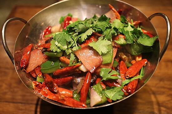 Colorful meat and vegetable bowl with cilantro on a rustic wooden surface.