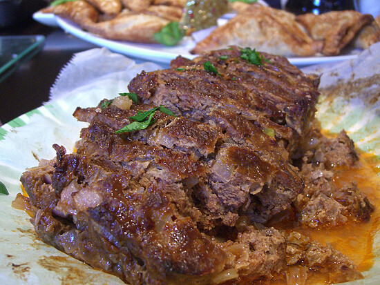 Savory meatloaf sliced, glazed, and served with crispy fried pastries, perfect comfort food.