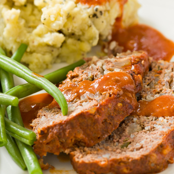 Hearty meatloaf with creamy mashed potatoes and fresh green beans on a plate.