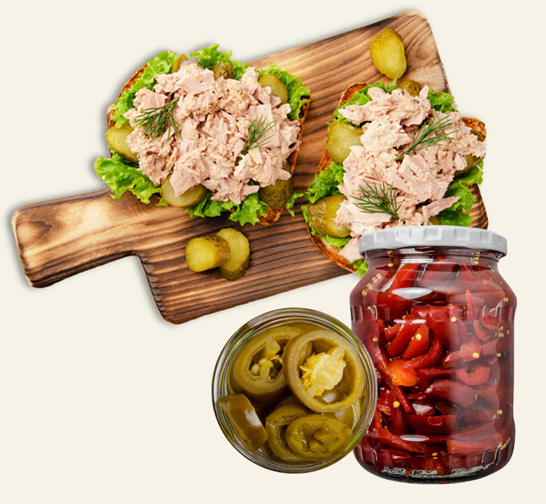 Delicious open-faced tuna sandwiches with pickles and fresh vegetables on a wooden board.