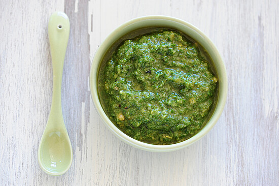 Fresh basil pesto in a rustic bowl with a pale green spoon, highlighting culinary versatility.