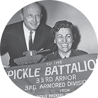 Celebrating the 33rd Armored Divisions Pickle Battalion with smiles, camaraderie, and a tank model.