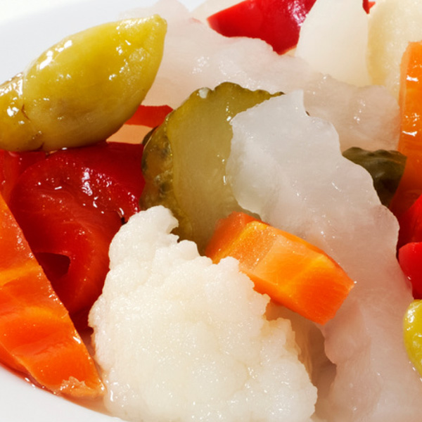 Vibrant pickled vegetable assortment featuring colorful cauliflower, carrots, olives, and cucumbers.