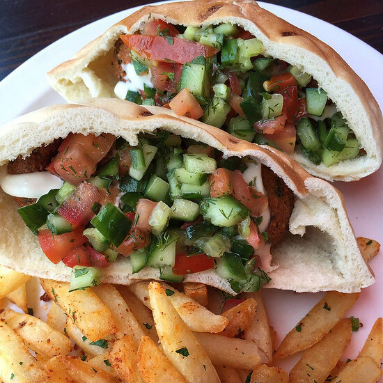 Fresh pita sandwiches with vegetables, falafel, and crispy seasoned fries for a delicious meal.