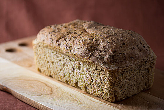 Artisanal rustic rye bread loaf on a wooden board, evoking warmth and homemade comfort.