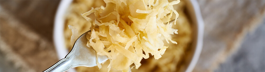 Close-up of fork with shredded sauerkraut, emphasizing its texture and rustic presentation.