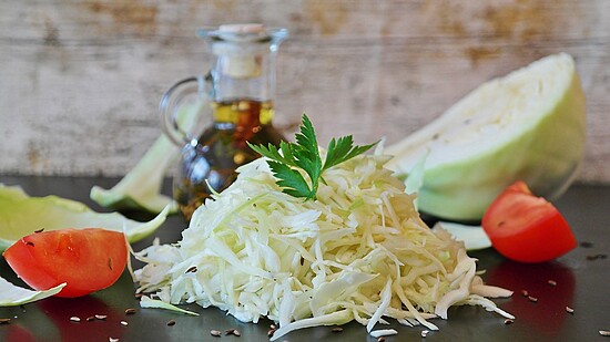 Fresh shredded cabbage and vibrant tomato ready for a healthy salad with olive oil.