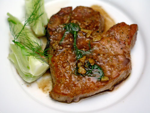 Succulent pork chop garnished with dill, served with tender cabbage for a gourmet presentation.