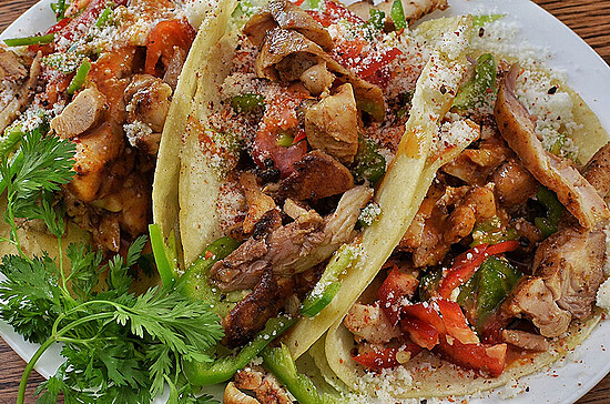 Delicious grilled chicken tacos with fresh vegetables and cheese on a rustic plate.