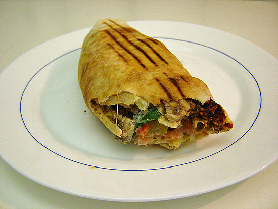 Savory grilled wrap filled with seasoned meat and fresh vegetables, served on a stylish plate.