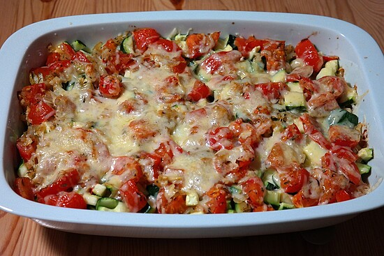 Delicious cheesy zucchini and tomato casserole, baked to perfection in a rustic white dish.